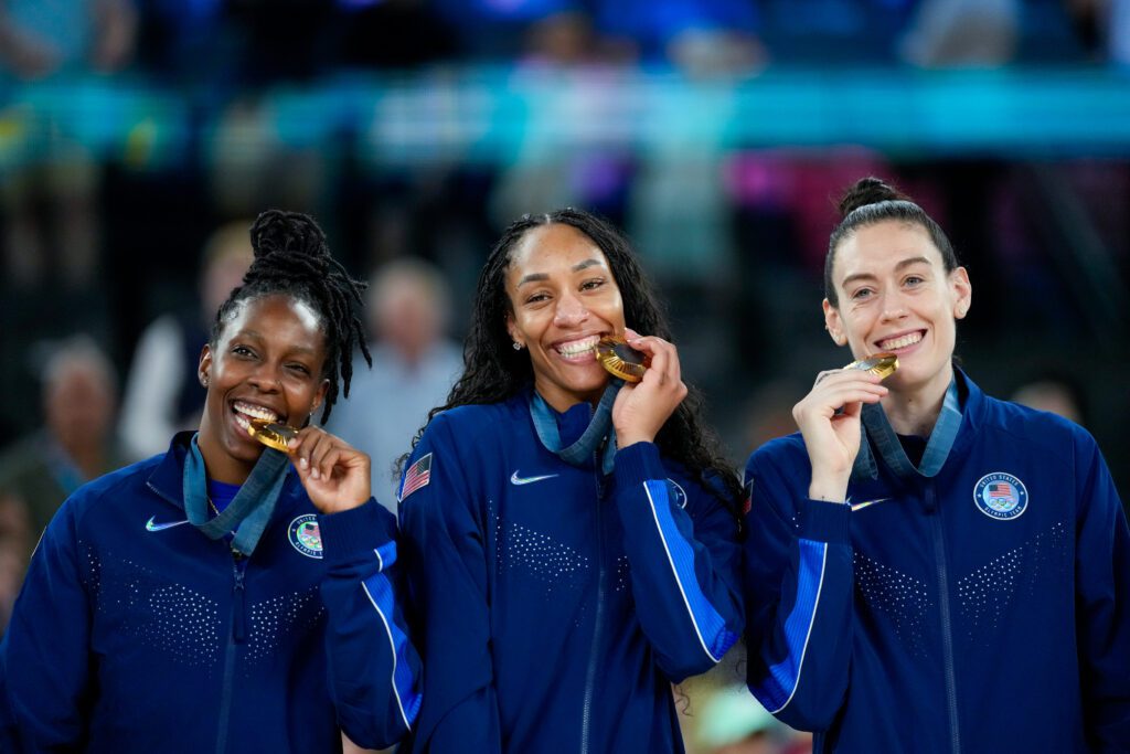 Chelsea Gray, A'ja Wilson, and Breanna Stewart bite their 2024 Olympic gold medals