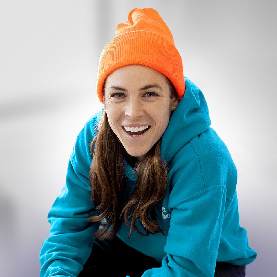 Sports Are Fun! host and soccer icon Kelley O'Hara poses in a blue hoodie and orange cap.