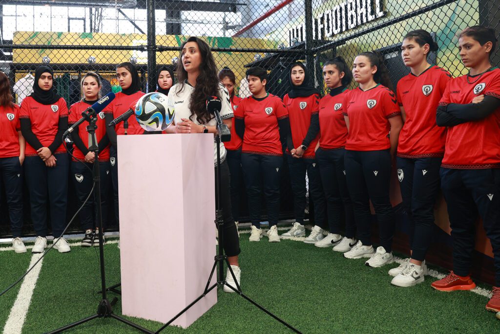 Afghan women's soccer team founder and director Khalida Popal speaks at a 2023 event surrounded by the squad in Australia.
