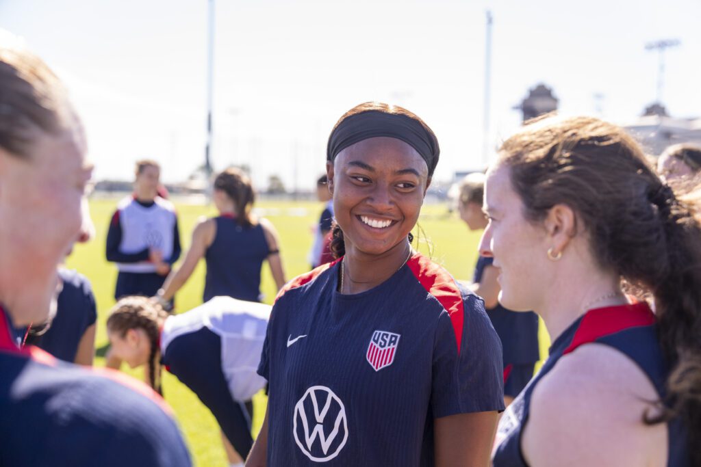 USWNT forward Jaedyn Shaw talks with defender Emily Sonnett and midfielder Rose Lavelle during an October 2025 training session.