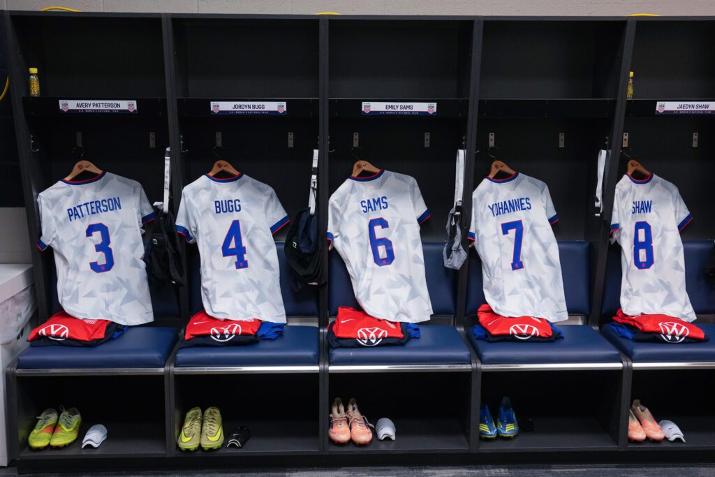 USWNT jerseys for Avery Patterson, Jordyn Bugg, Emily Sams, Lily Yohannes, and Jaedyn Shaw hang in a locker room before a 2025 friendly.