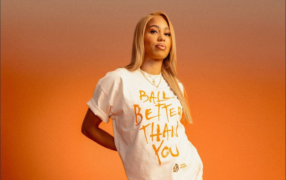 New York Liberty forward Izzy Harrison models a T-shirt that says "Ball Better Than You" from the new Playa Society "Love & Basketball" collection.