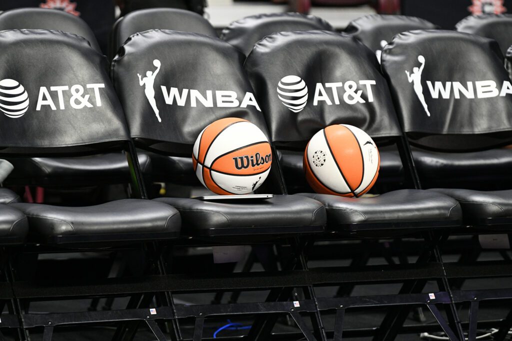Two basketballs rest on a row of WNBA and AT&T branded chairs before a 2025 game.