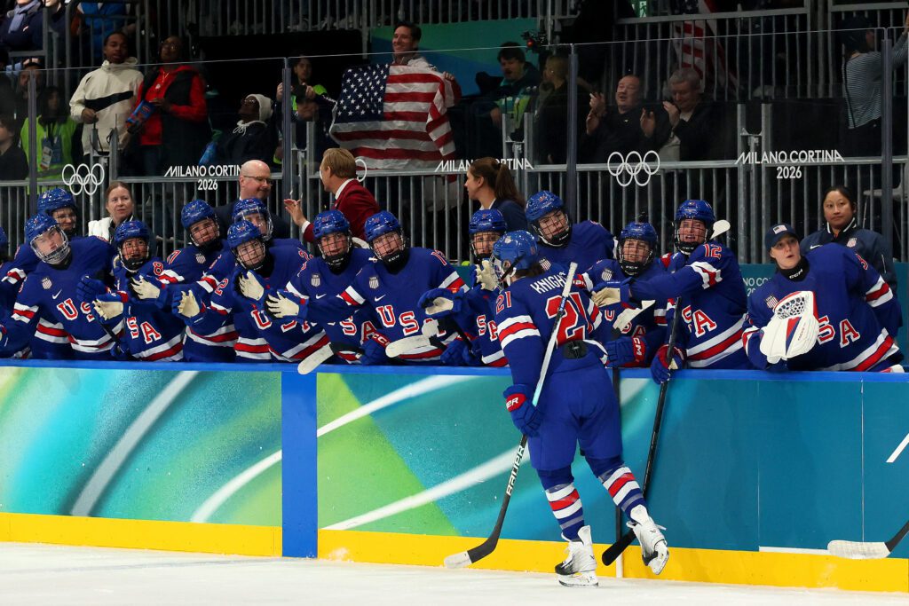 The Team USA hockey bench high-fives captain Hilary Knight after her goal against Finland in group-play at the 2026 Olympics.