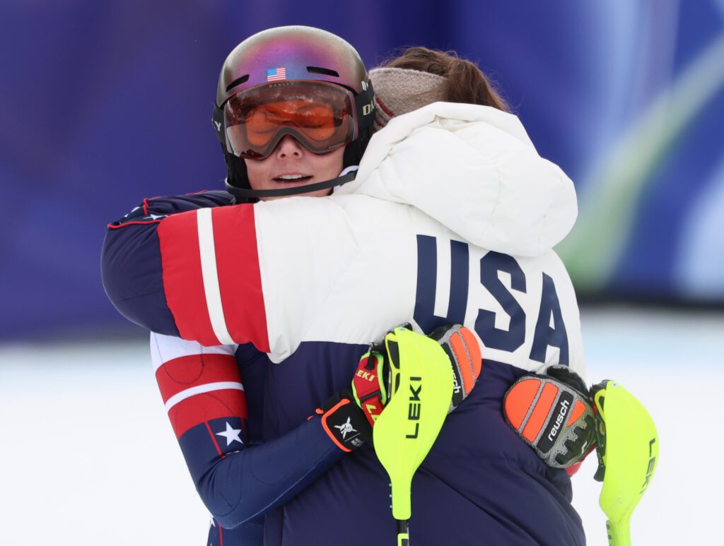 USA ski star Mikaela Shiffrin hugs a teammate after a disappointing slalom run in the women's team combined at the 2026 Winter Olympics.